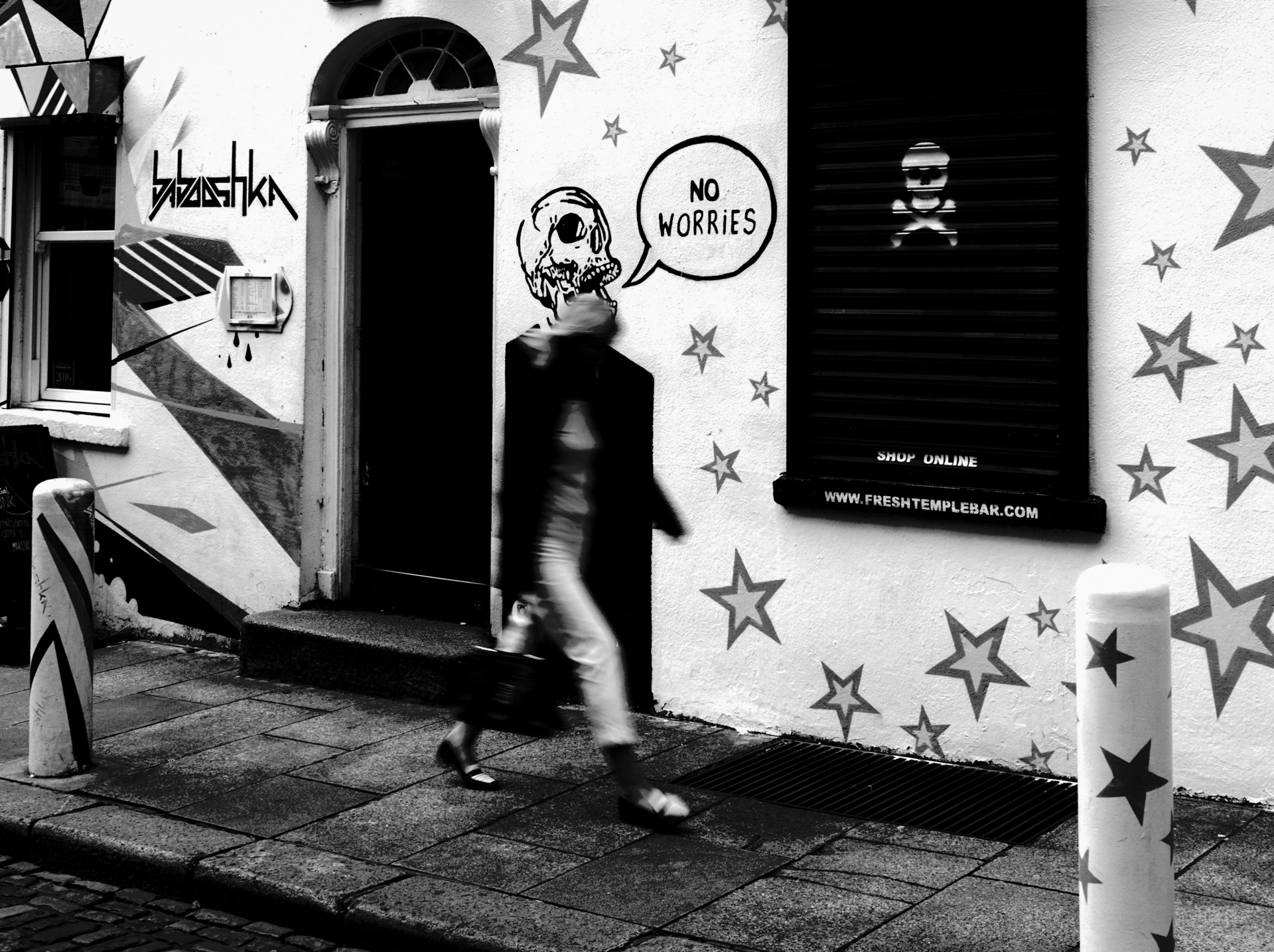 Woman walking past a painted facade with stars and a speech bubble.