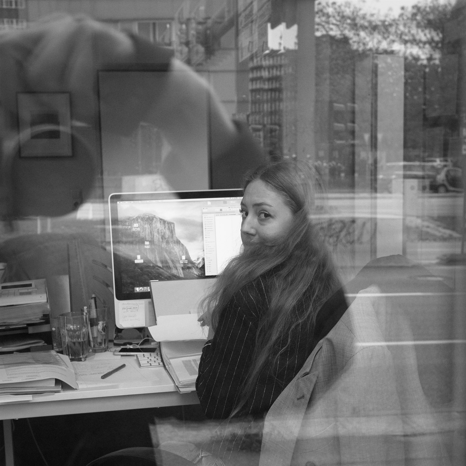 Woman behind an office window among reflections.
